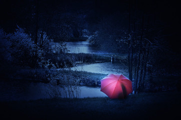 At a rainy night sitting under a red umbrella with a flashlight