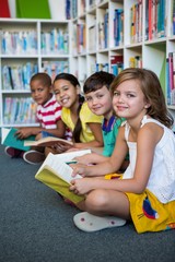 Smiling students sitting at library in school