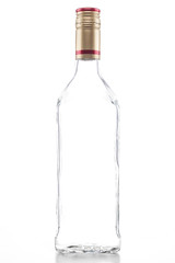 Isolated empty clear tequila bottle with a gold and red cap on a white background
