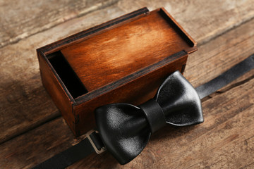 Leather bow tie and gift box on wooden background