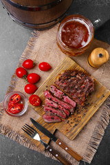 Tasty grilled steak with beer on cutting board