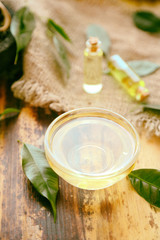 Glass bowl with tea oil on wooden background