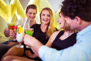 Happy friends toasting cocktail glasses