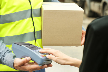Delivery concept. Postman giving packages to woman, woman paying for service