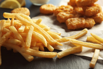 Tasty nuggets and fries on table, closeup