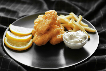 Tasty chicken nuggets with fries, sauce and lemon on plate