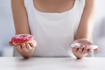 Woman with donut and blood sugar level at home