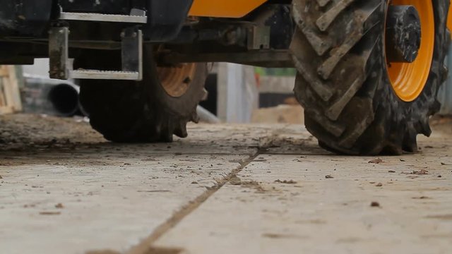 The tractor moves the cargo on the construction site. Close-up of wheels , dolly shot