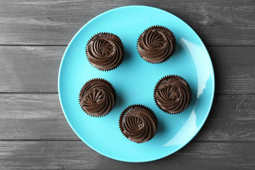 Tasty cupcakes on blue plate, top view