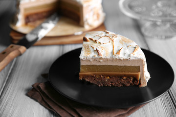 Slice of delicious cake with chocolate, nuts and pear topping on black plate