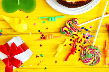 Birthday party objects on yellow wooden background, top view