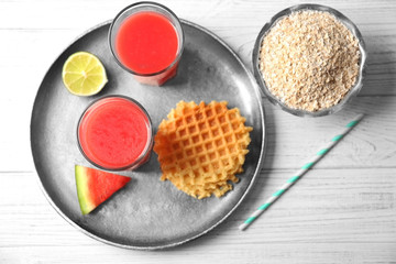 Glasses with fresh smoothie, watermelon slice and wafers on a tray