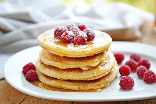 Stack of fresh pancakes with berries on white plate closeup