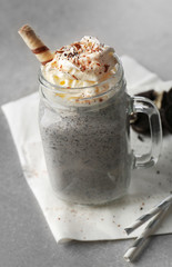 Delicious milk dessert with sweets in glass jug on table, closeup