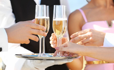 Waiter offering champagne to guests at party, close up view