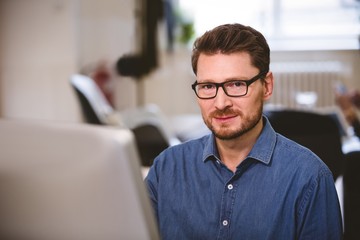 Fototapeta premium Portrait of confident executive with computer at office