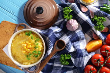 Tasty cornmeal porridge with parsley in a saucepan on table