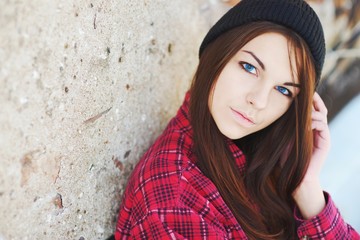 Portrait of young beautiful blue-eyed brunettes women around the concrete wall, closeup