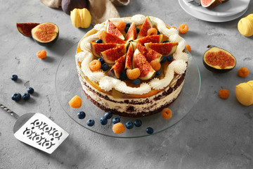 Delicious creamy cake with figs and berries on grey textured background