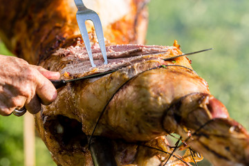 Roasting lamb barbecue - Roasted meat over an open fire - Woman cutting meat