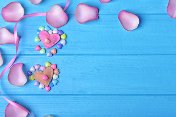 Handmade hearts and rose petals on blue wooden background