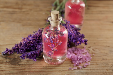 Bottle with aroma oil, sea salt and lavender flowers on wooden background