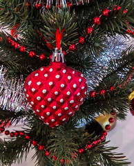 Closeup of red heart hanging from a decorated Christmas tree.