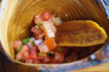 Bowl of fresh pico de gallo tomato salsa with a plantain chip © eqroy