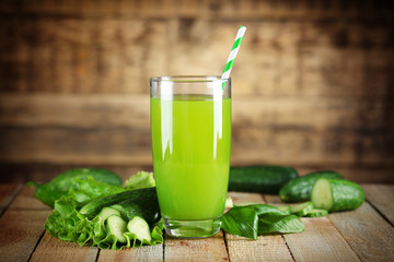 Glass with fresh cocktail and ripe vegetables on wooden wall background