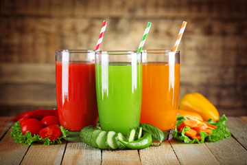 Glasses with fresh cocktail and ripe vegetables on wooden wall background