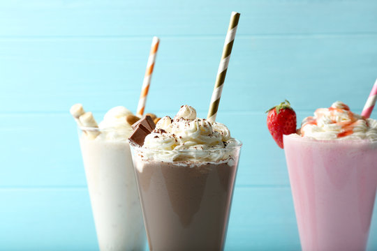 Delicious milkshakes on blue wooden background