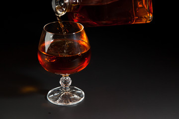 Cognac is poured from a bottle into  glass