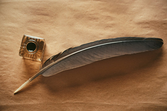 Feather pen and inkwell on paper background