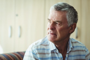 Thoughtful senior man sitting in living room