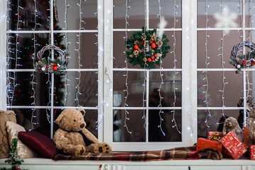 Holiday decoration on the windowsill covered with woolen plaid. Christmas wreath, 