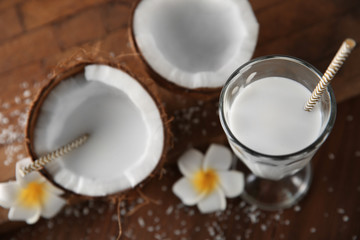 Tasty milk shake with coconut and flowers on table