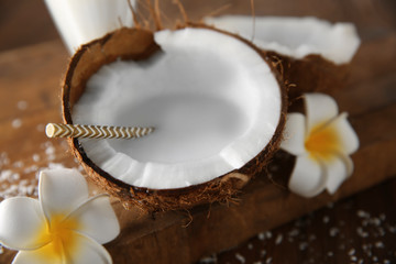 Tasty milk shake in coconut with flowers on table