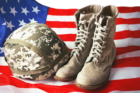 Pair of combat boots, military helmet and USA flag, close up view