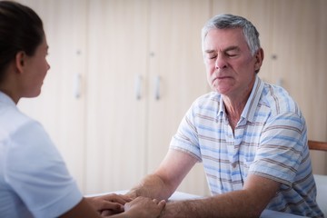 Obraz premium Female doctor consoling senior man