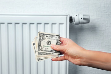 Woman holding money near heating battery