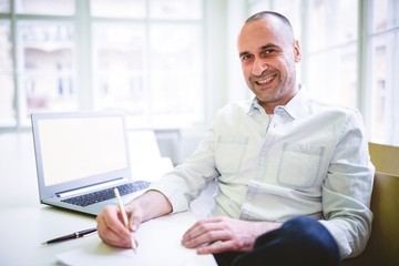 Smiling businessman writing document