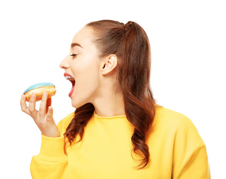 Funny young woman eating tasty donut on white background