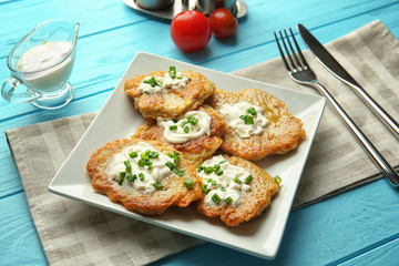 Plate with tasty potato pancakes for Hanukkah on wooden table