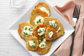 Plate with tasty potato pancakes for Hanukkah on wooden table