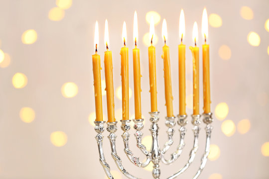 Menorah with candles for Hanukkah against defocused lights, close up