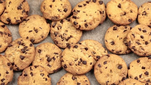 Slider shot of freshly baked chocolate chip cookies laid out on a stone worktop