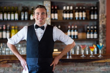 Portrait of confident waiter standing with hands on hip