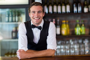 Portrait of bartender leaning on bar counter