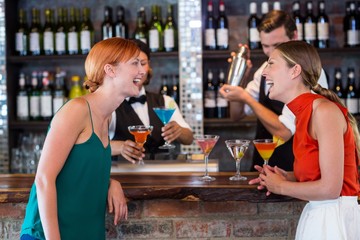 Friends standing at counter while bartender preparing a drink