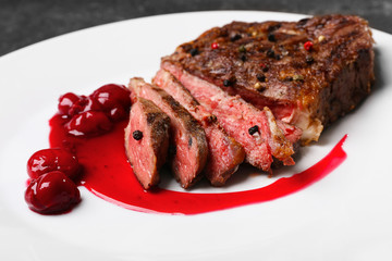 Sliced tasty steak with spices and sauce on white plate